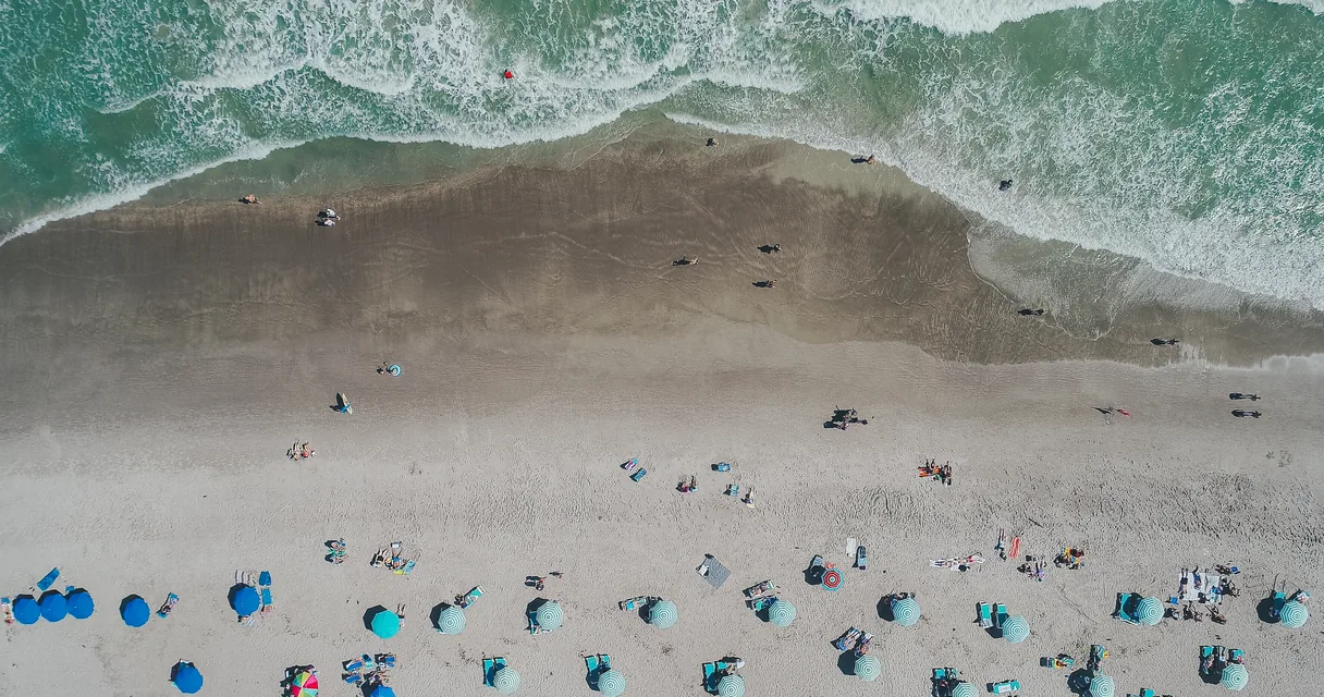 Praia vista do alto com guarda-sóis e a ondulação do mar, ilustrando como funciona o pagamento das férias