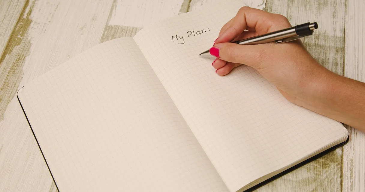 Agenda aberta com uma caneta sobre a mesa, ilustrando a escala 5x2 e como funciona